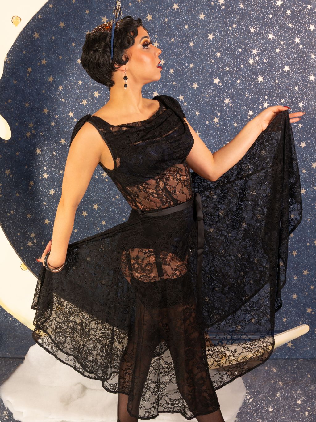 Woman in a black lace dress against a starry night sky background