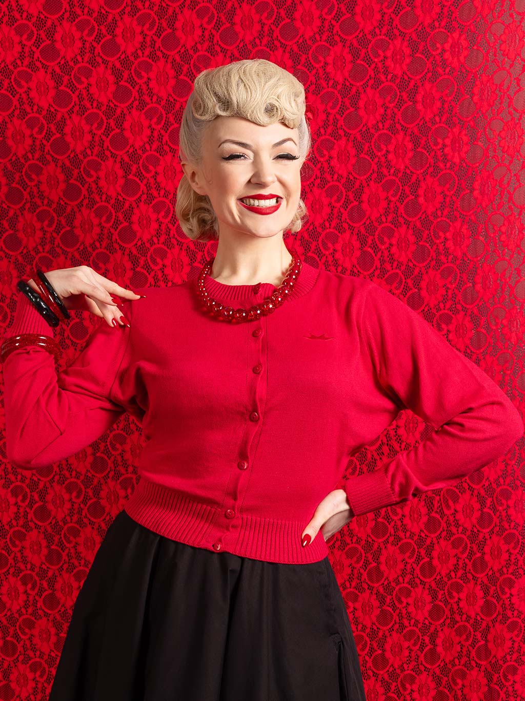 1950s retro red cardigan worn with a black circle skirt and 1950s red confetti jewellery