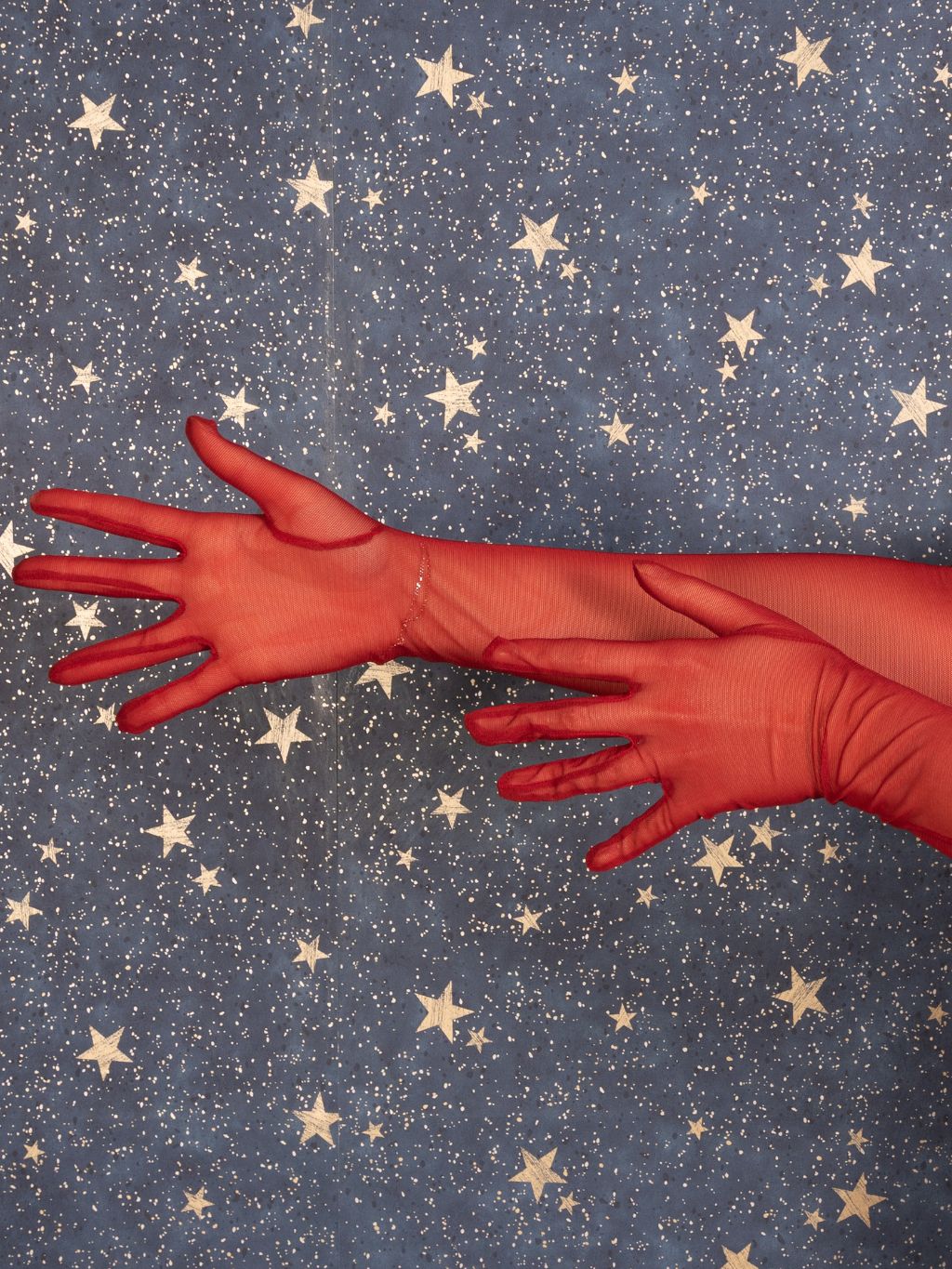 Red gloves on a blue fabric background with star patterns