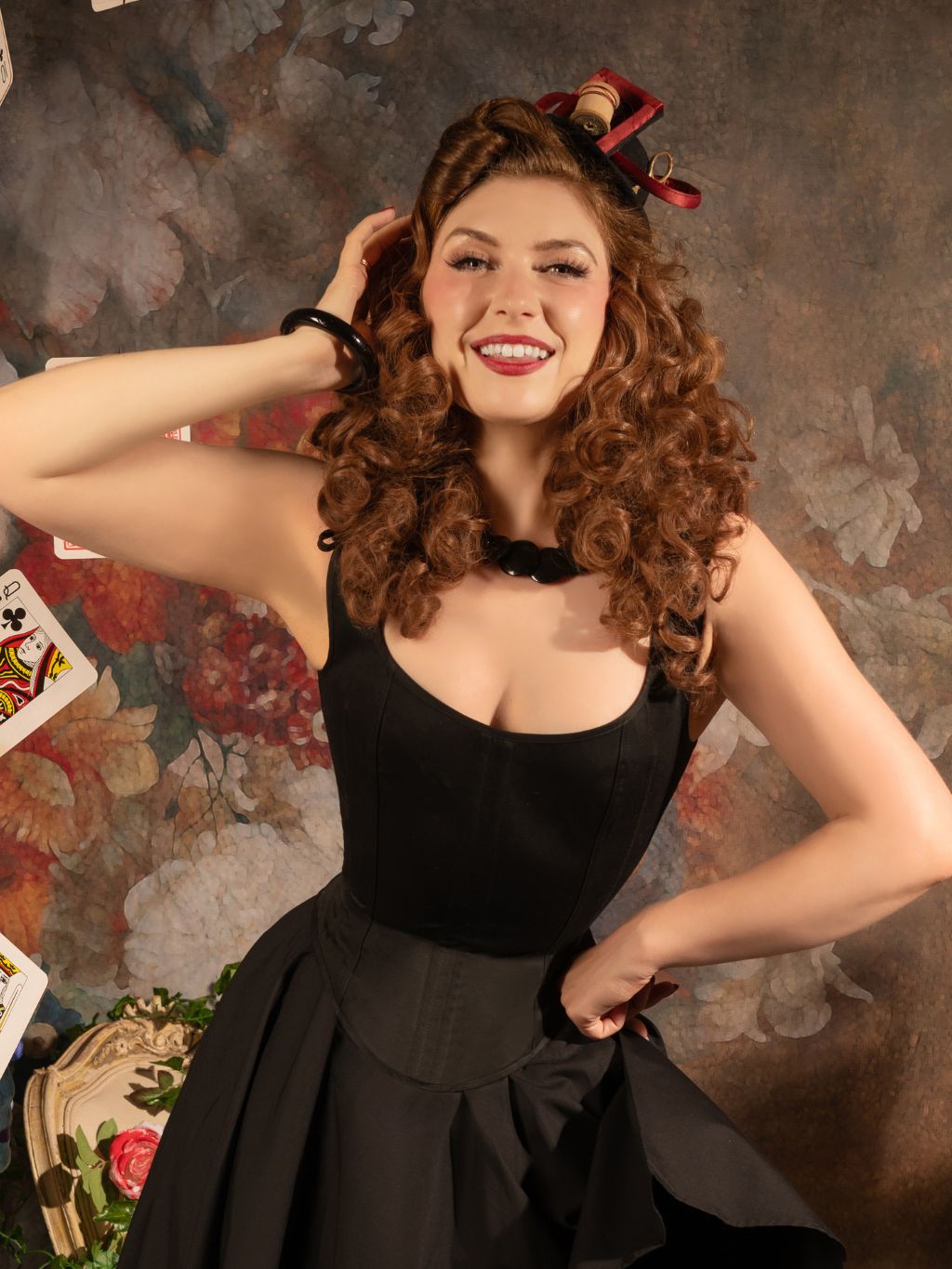 Woman in a black dress posing against a decorative background