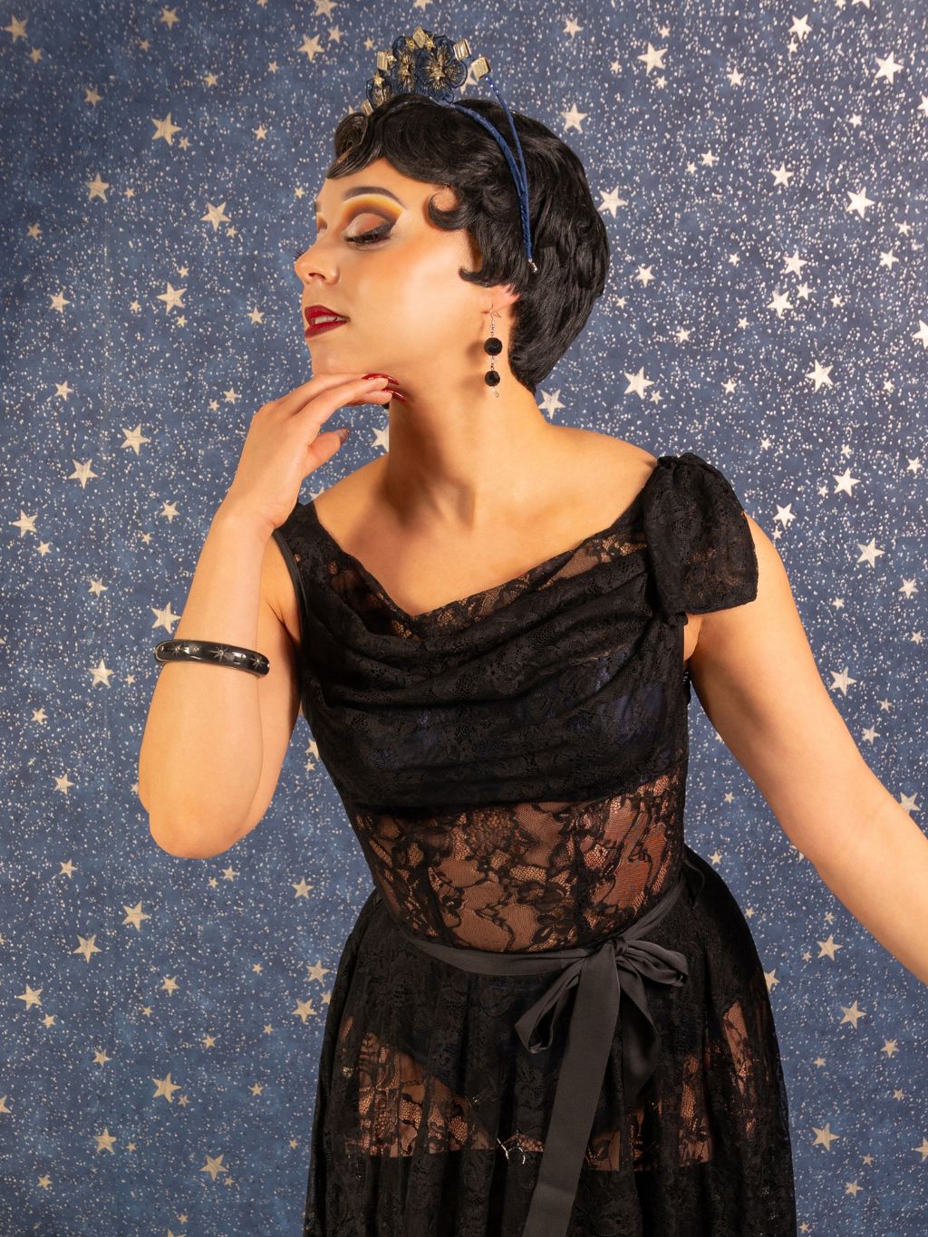 Woman in a black lace dress against a starry background