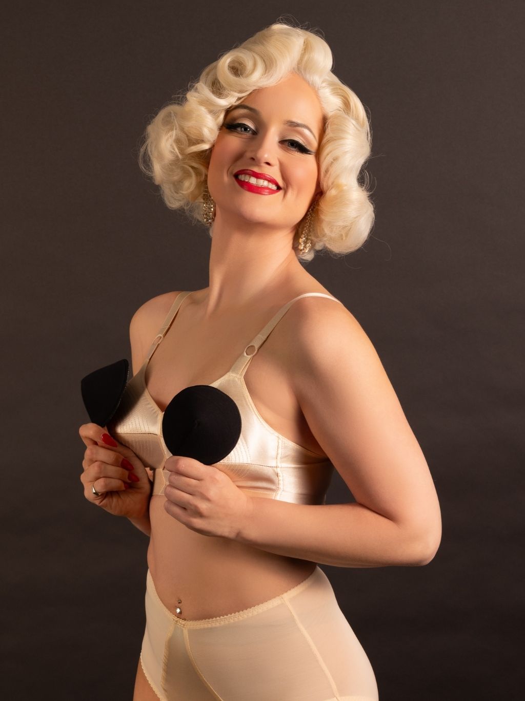 Person wearing a blonde wig and peach bullet bra with bullet bra pads against a dark background