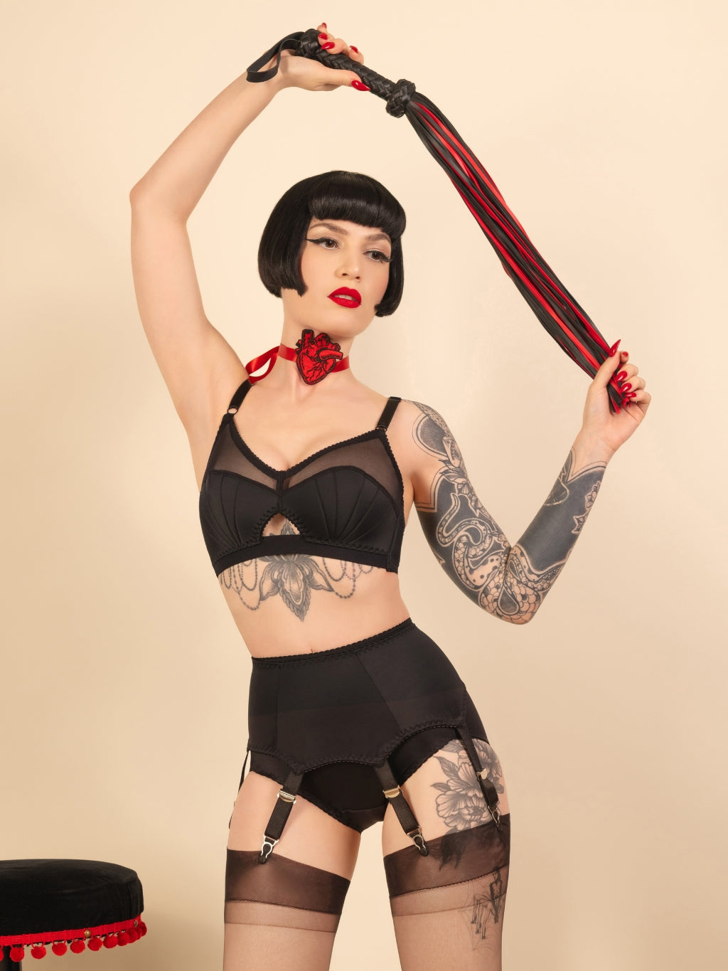 Woman in black retro lingerie and garter belt against a beige background