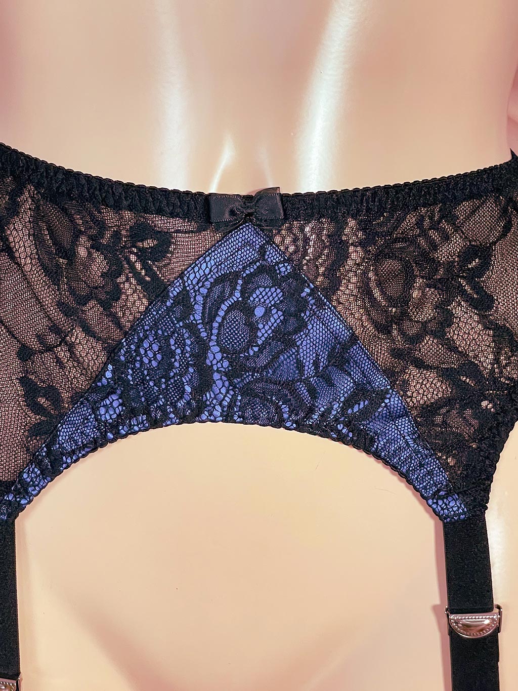 still life image close up of a blue and black lace garter belt by what katie did