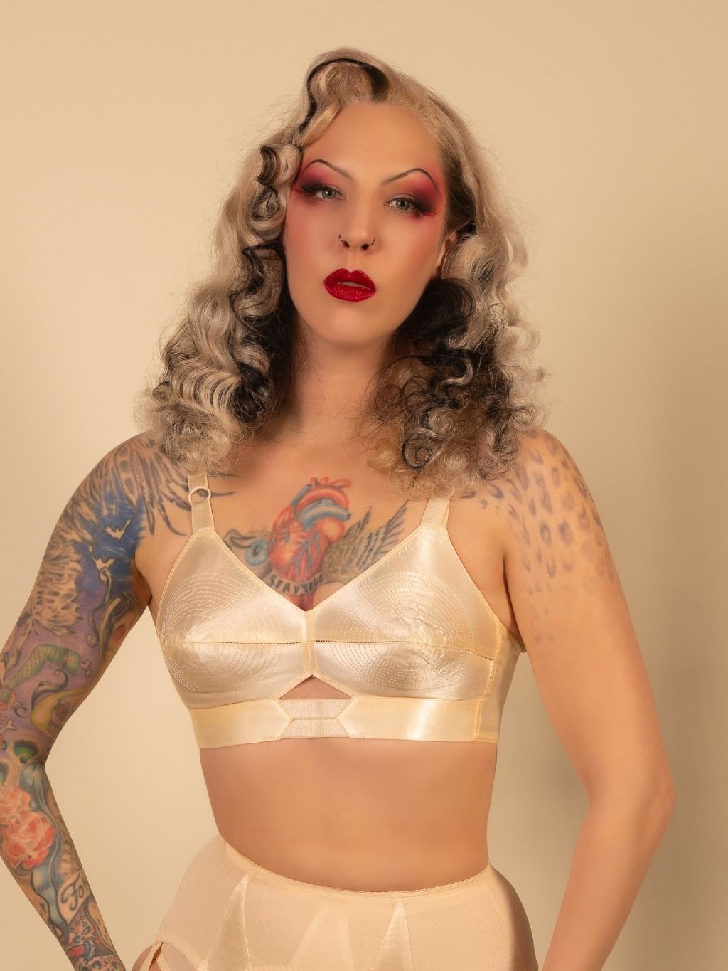 Woman wearing a peach satin bullet bra against a beige background