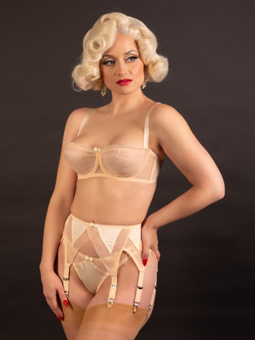 Woman wearing a sheer peach vintage lingerie  set against a dark background
