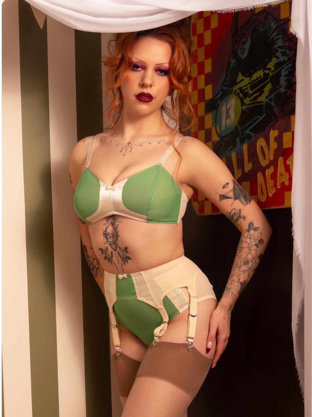 Green suspender belt with 6 straps and semi-sheer georgette panel on vintage-styled redhead model, front view