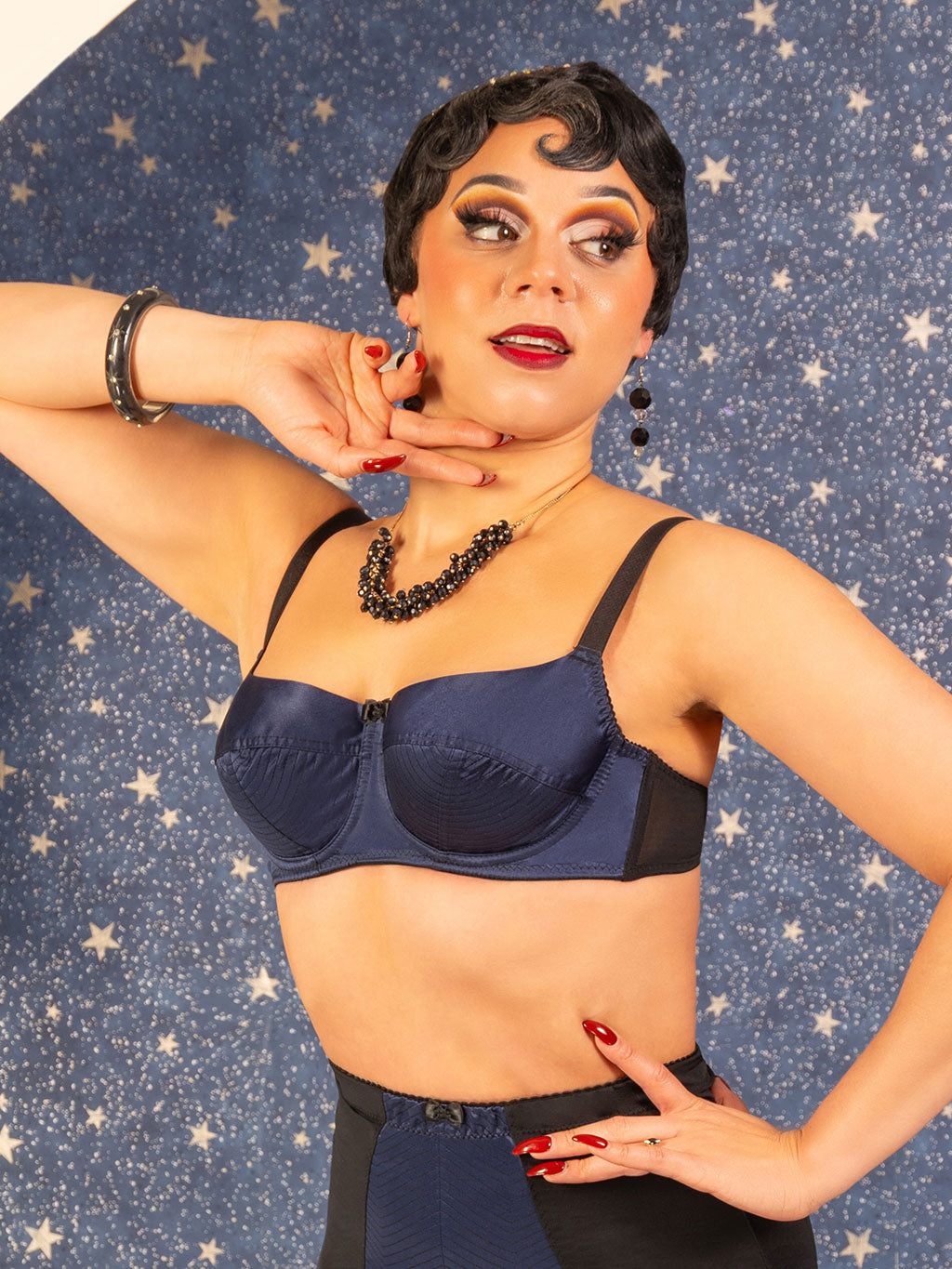 Woman wearing a blue bralette against a star-patterned background