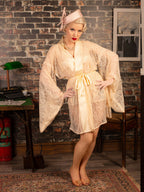 Woman in a vintage-style dress standing in a room with brick walls and a desk.