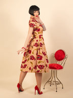 Woman wearing a floral dress standing next to a red cushioned chair on a beige background