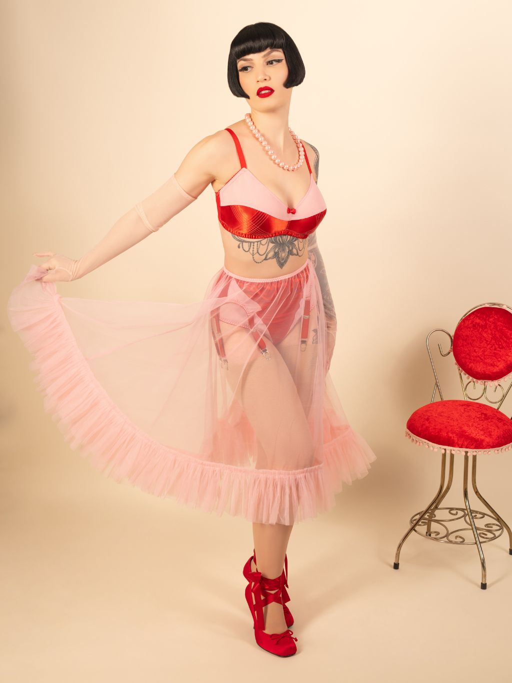 Woman in vintage-inspired red and pink lingerie with sheer frilly pink petticoat.