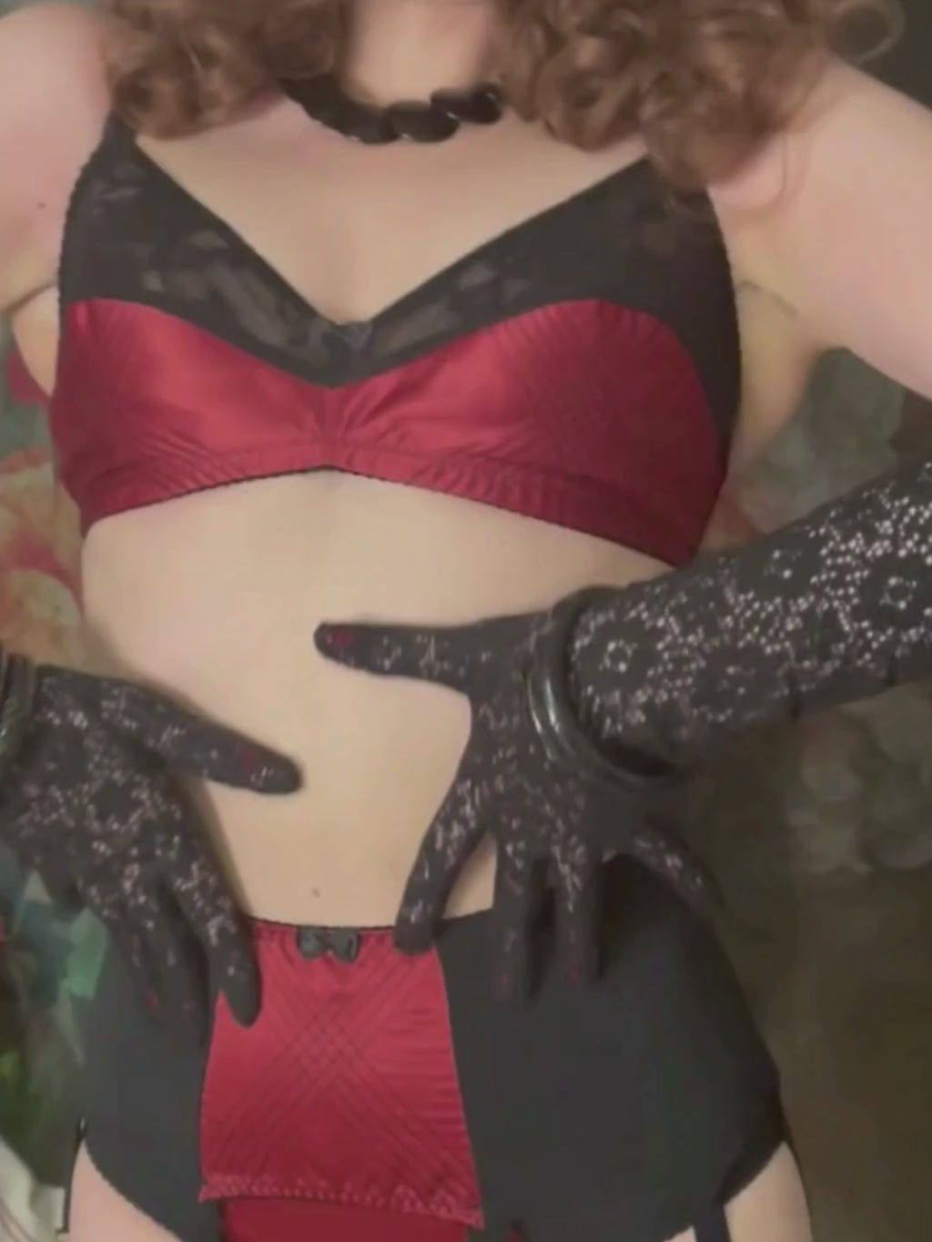 Woman wearing a black lingerie set with a decorative hat against a floral background