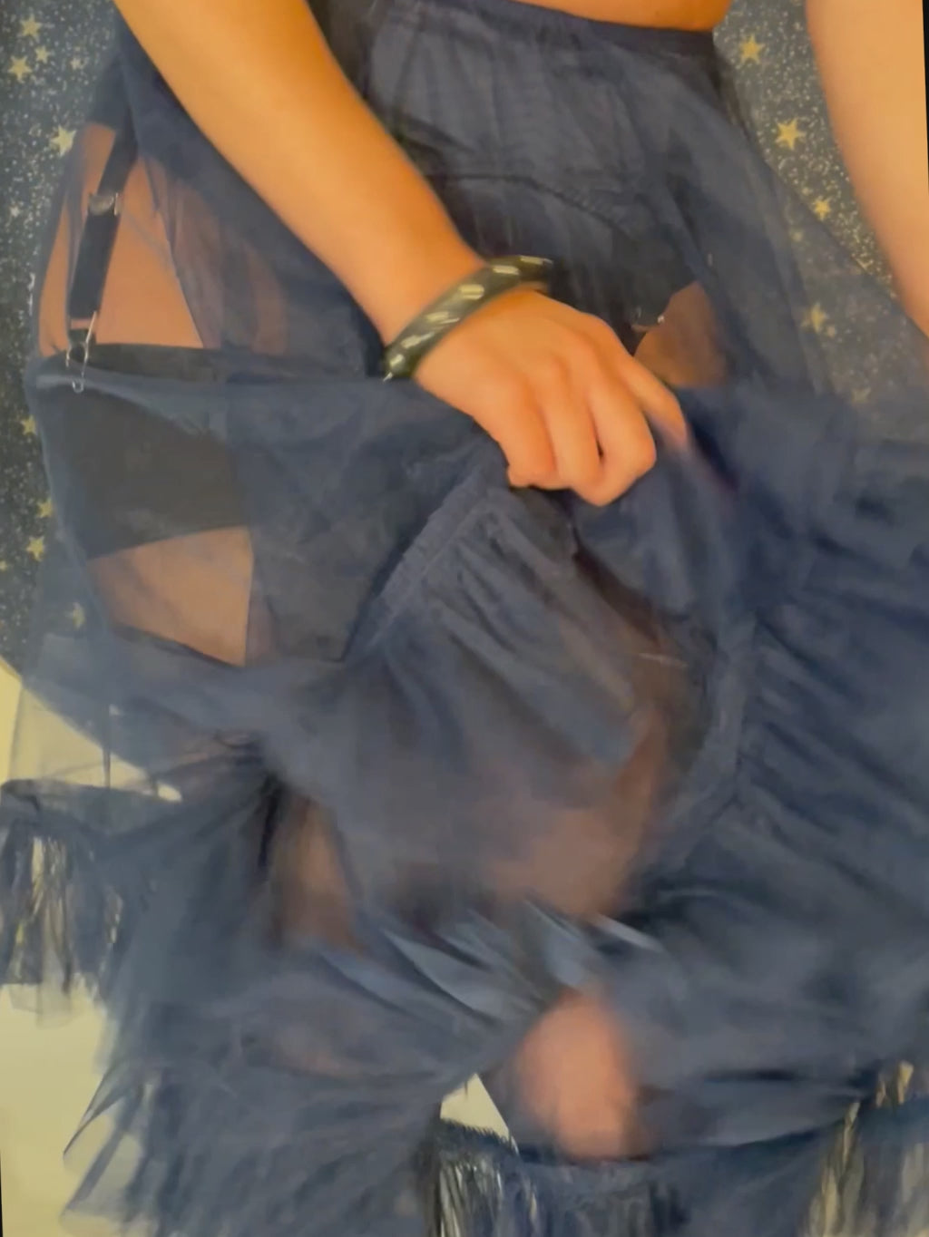 video of a woman in a 1950s navy blue frilly petticoat and lingerie in front of a moon and star background
