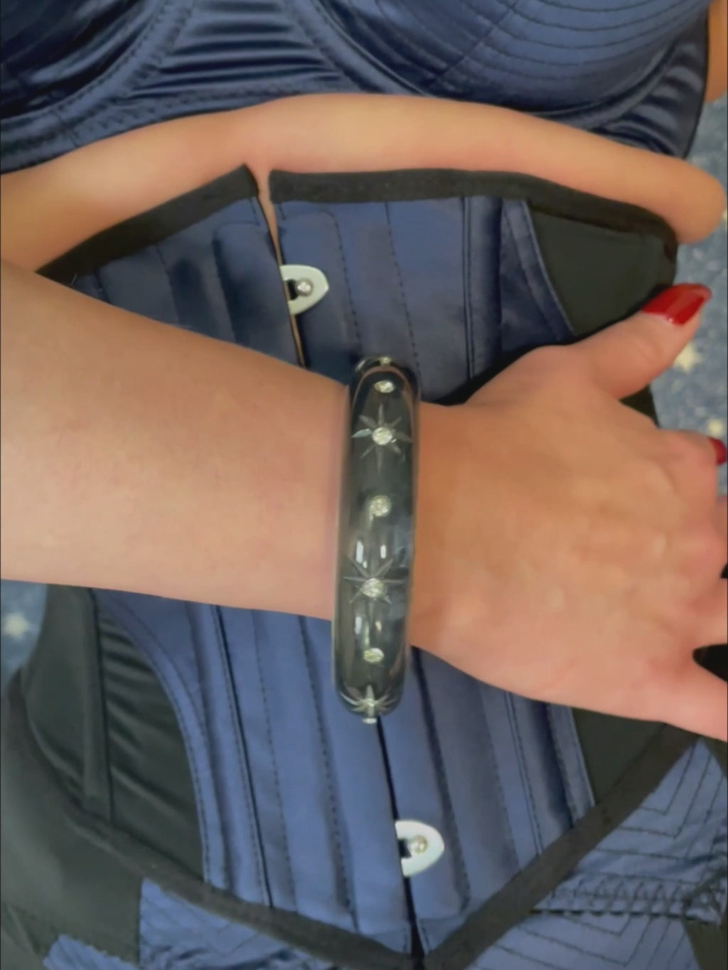 Video of a woman wearing a navy blue corset against a star-patterned background