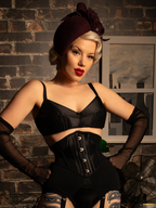 Woman wearing a black satin bralette with a beige background