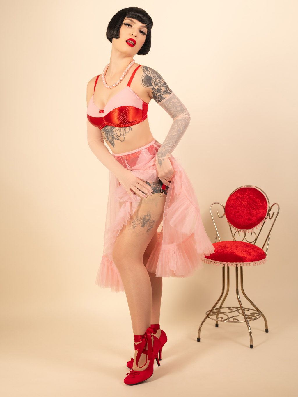 Woman in vintage-inspired red and pink lingerie with sheer frilly pink petticoat.