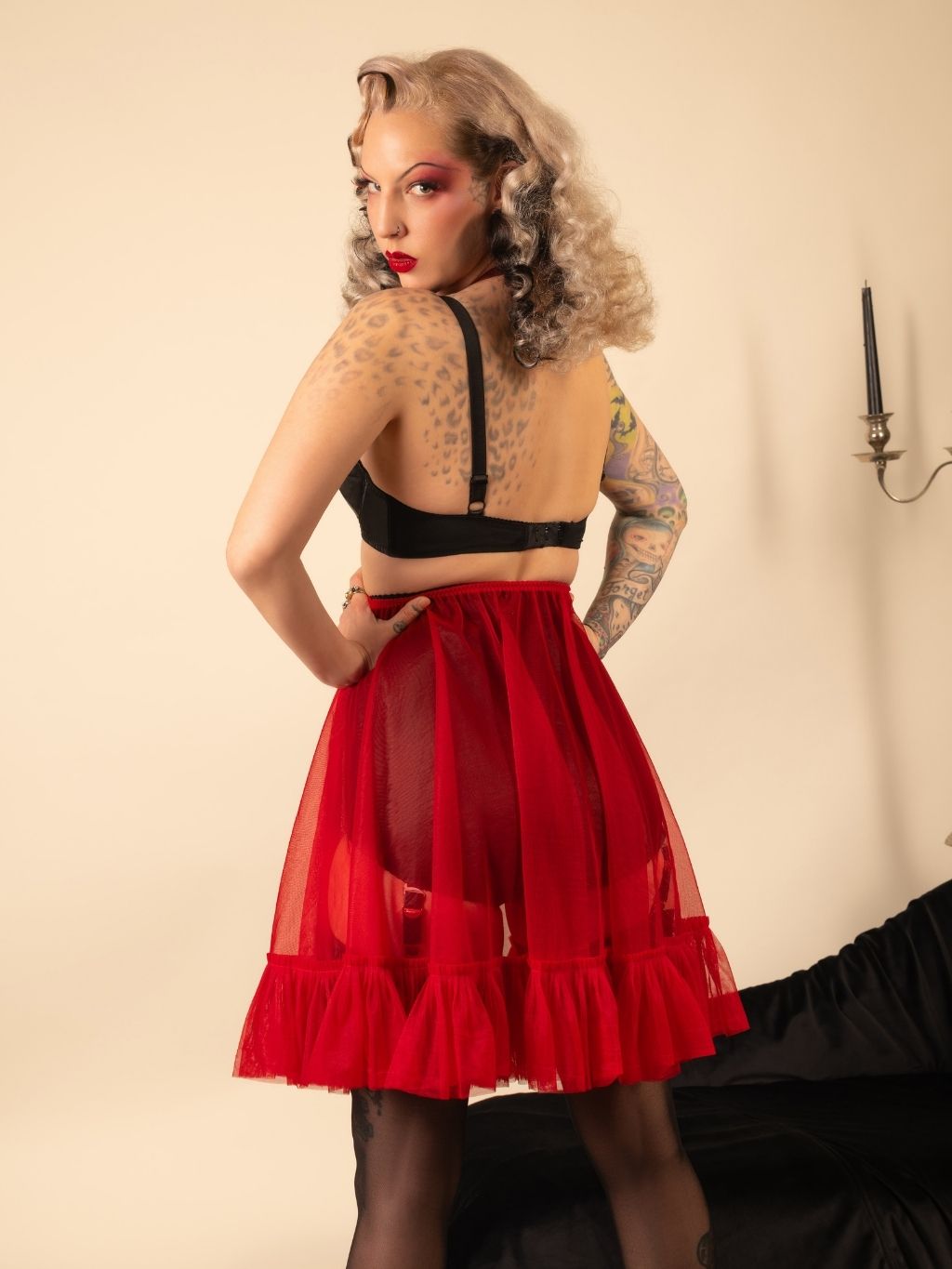 Woman wearing a black bra and red frilly petticoat with a neutral background