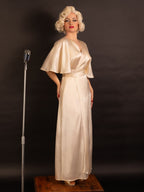 Person in a vintage-style peach satin robe standing next to a microphone on a dark background