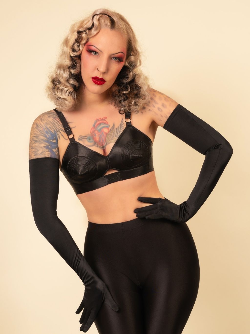Woman wearing a black bra and long gloves against a beige background