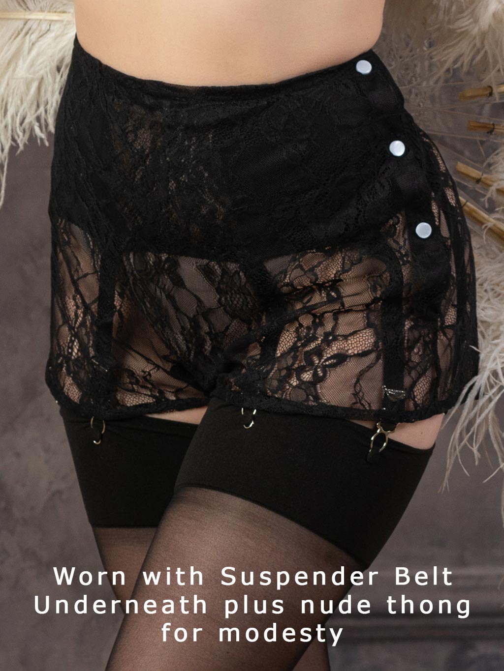 close up of 1940s black lace knickers showing the  faux pearl side buttons , worn with matching suspender belt and black seamed stockings