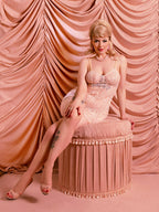 Model sitting on velvet stool in peach vintage lace romper