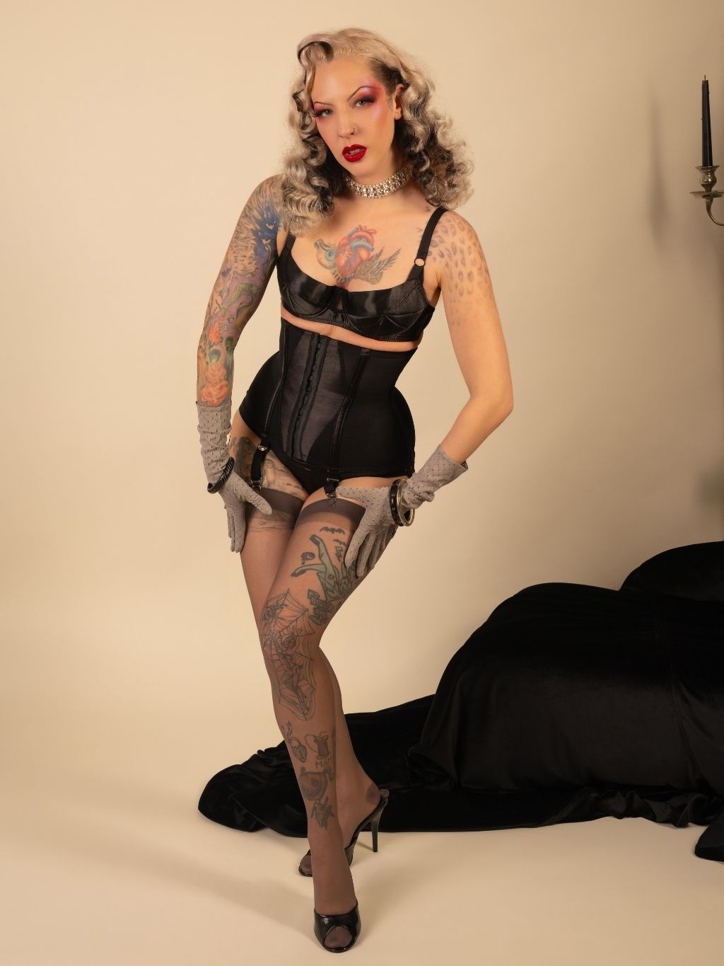 Woman in black lingerie and stockings posing against a beige background