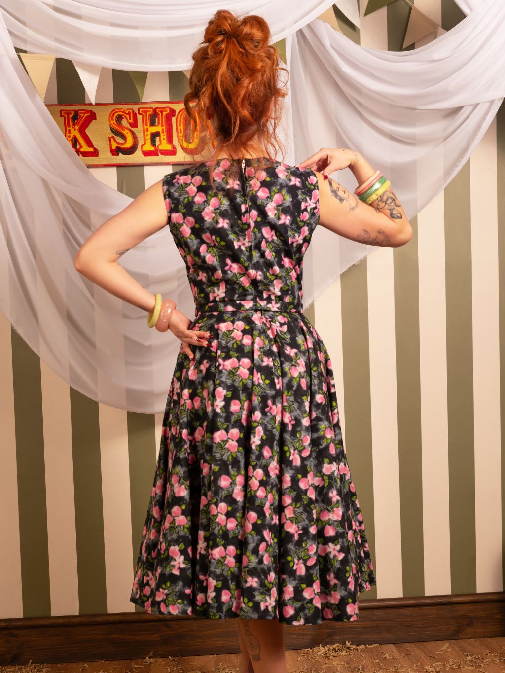 Back view of Wilhelmina 1950s grey floral dress showing full circle skirt and practical pockets - worn by redhead model